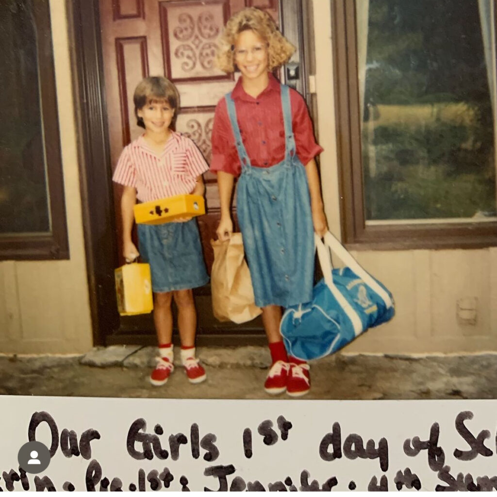 2 girls in their back to school outfits, one wearing very large glasses with permed hair